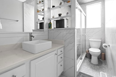 Bathroom with a marble finish shower, vanity, tile