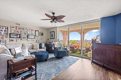 Living area with wood finished floors, expansive windows, a textured ceiling, and a ceiling fan