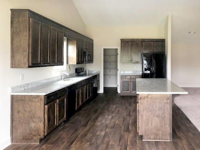 Kitchen with black appliances, a sink, vaulted cei