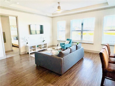Living room featuring ceiling fan, a tray ceiling,