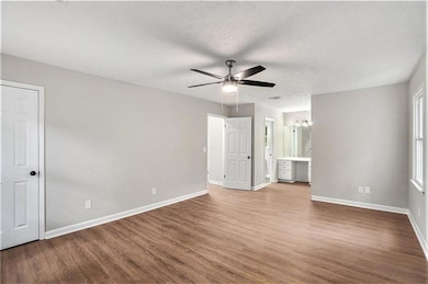 Empty room with ceiling fan, wood-type flooring, and a textured ceiling