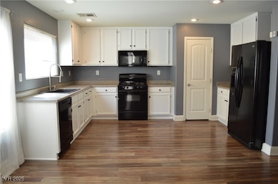 Kitchen featuring black appliances, a sink, dark w