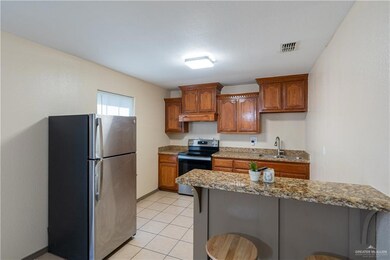 Kitchen with a kitchen bar, freestanding refrigerator, electric range, and brown cabinets