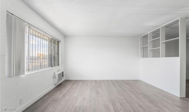 room with a wall mounted AC, wood finished floors,