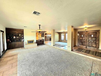 Living area with light tile patterned floors, light carpet, a fireplace, a textured ceiling, and a ceiling fan