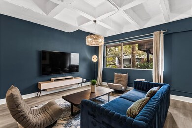 Living area with coffered ceiling, beam ceiling, wood finished floors, and a chandelier