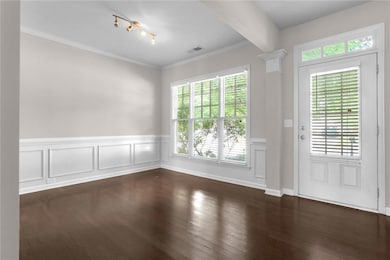 Foyer entrance featuring healthy amount of natural light, wainscoting, crown molding, dark wood finished floors, and a decorative wall
