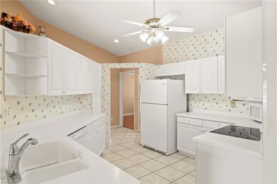 Kitchen featuring white appliances, wallpapered walls, a sink, ceiling fan, and light tile patterned flooring