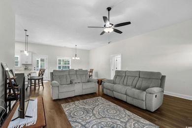 Living room with dark wood finished floors, a chandelier, a ceiling fan, and a textured ceiling