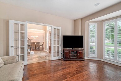 Private study with wood flooring, bay window, plantation shutters and French doors.