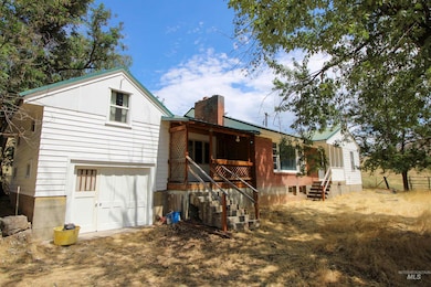 Rear view of property with a chimney, covered porch, and an attached garage