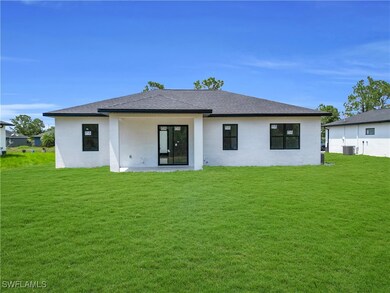 Rear view of house featuring a yard, stucco siding
