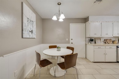 Dining space featuring light tile patterned floors, a chandelier, and a wainscoted wall