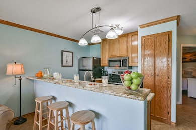 This kitchen features granite countertops, stainless steel appliances, and wooden cabinetry. It has a double sink, tile flooring, and ample lighting, creating a warm and functional space.