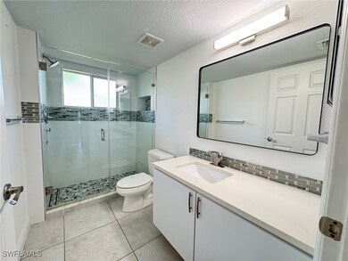 Full bathroom featuring vanity, a textured ceiling, a stall shower, light tile patterned floors, and backsplash