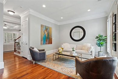 Living area with wood finished floors, recessed lighting, crown molding, baseboards, and stairway