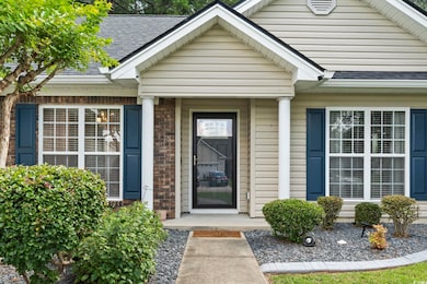 View of exterior entry with a shingled roof and brick siding