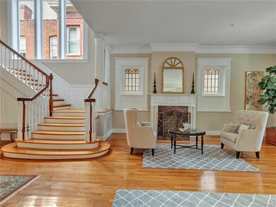 Stair hall with sweeping staircase and soaring triple window that bathes first floor in light.