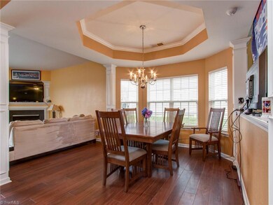 Formal open concept dining room with trayed ceiling and bay window.