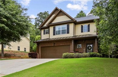 View of front of home featuring a standing seam roof, a garage, a front lawn, and brick siding