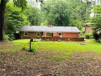 Back of house with a lawn, brick siding, and a chi