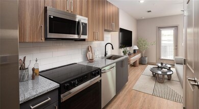 Kitchen with light stone countertops, appliances with stainless steel finishes, light wood-style floors, tasteful backsplash, and modern cabinets