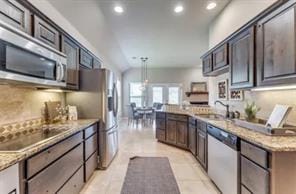 Kitchen featuring pendant lighting, a peninsula, appliances with stainless steel finishes, recessed lighting, and vaulted ceiling