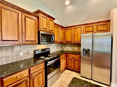 Kitchen with backsplash, vaulted ceiling, light ti