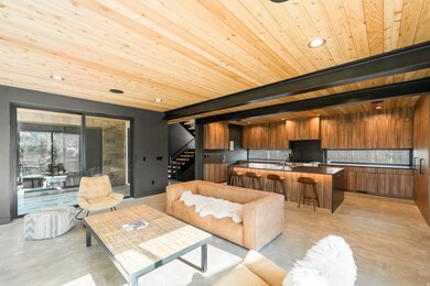 Living area featuring finished concrete flooring, stairs, recessed lighting, and a wooden ceiling with exposed beams