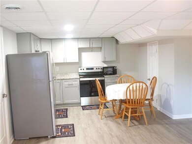 Kitchen with stainless steel appliances, light wood finished floors, a drop ceiling, baseboards, and gray cabinetry