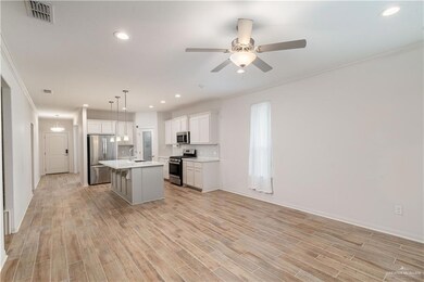 Kitchen with stainless steel appliances, a sink, a ceiling fan, crown molding, and light countertops