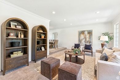 Living room with light colored carpet, crown molding, and recessed lighting