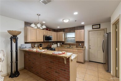 Kitchen with an inviting chandelier, kitchen peninsula, appliances with stainless steel finishes, sink, and decorative light fixtures