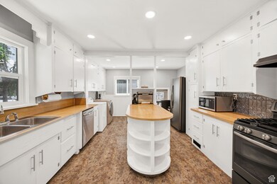 Kitchen featuring appliances with stainless steel finishes, open shelves, white cabinets, backsplash, and recessed lighting