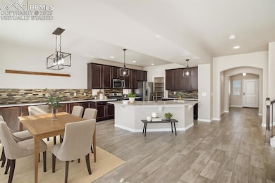 Virtually staged Dining space with arched walkways, recessed lighting, light wood finished floors, and baseboards