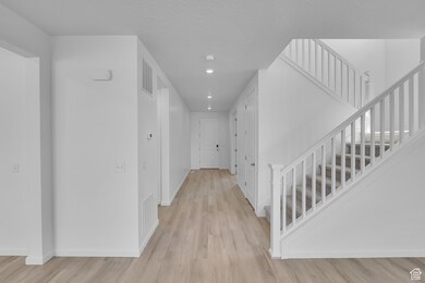 Hallway with light wood-style flooring, stairs, a textured ceiling, and recessed lighting