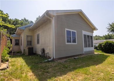 View of side of home with central air condition unit and a lawn