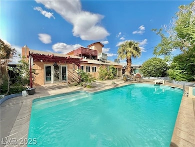Rear view of property featuring a patio, an outdoor pool, stucco siding, and a pergola
