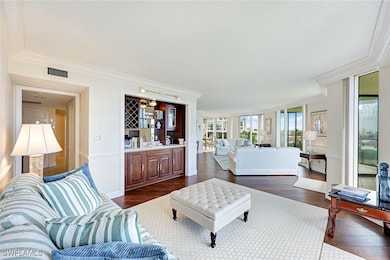 Living room featuring crown molding, dark wood-style floors, bar, and expansive windows