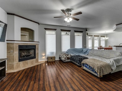 Bedroom with a chandelier, wood finished floors, ceiling fan, and a fireplace