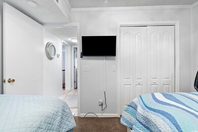 Bedroom featuring a closet, carpet flooring, a textured ceiling, and crown molding