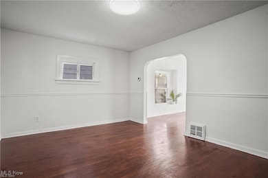 Living room with arched walkways, plenty of natural light, and wood floors.
