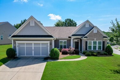 View of front facade featuring concrete driveway, a front yard, a garage, brick siding, and a standing seam roof