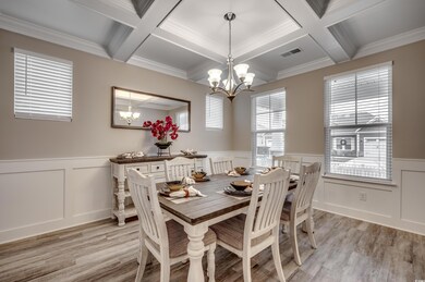 Dining space featuring a decorative wall, coffered ceiling, a chandelier, light wood-style flooring, and beam ceiling