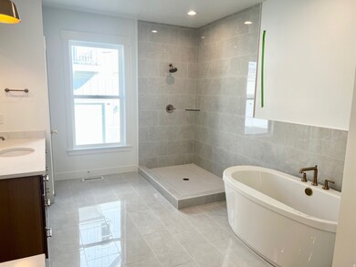 Bathroom with a freestanding tub, light tile patterned floors, vanity, a tile shower, and tile walls
