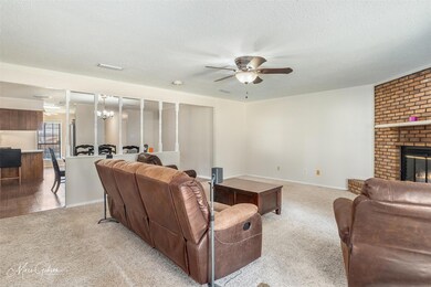 Carpeted living room with ceiling fan, a textured 