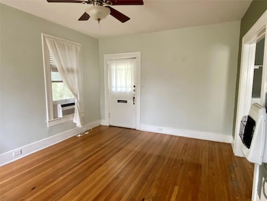 Unfurnished living room with hardwood / wood-style flooring, heating unit, and a ceiling fan