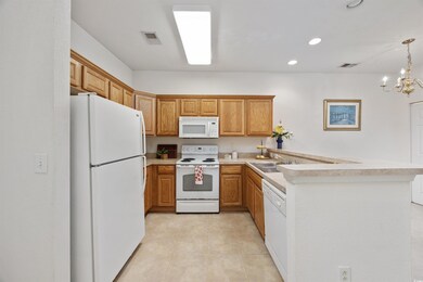 Kitchen with white appliances, a peninsula, light countertops, light tile patterned flooring, and recessed lighting