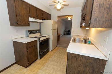 Kitchen with electric range, dark brown cabinets, a textured ceiling, light countertops, and a ceiling fan