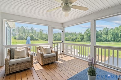 Sunroom featuring ceiling fan and view of scattered trees